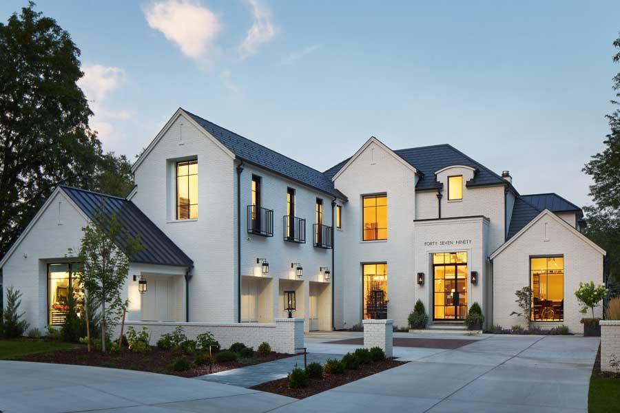 A modern Tudor home makes a high-contrast statement with white painted brick and black-framed Andersen windows.