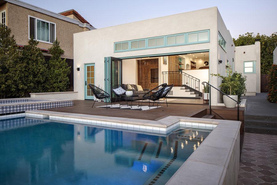 A backyard swimming pool and deck connect to the house through a bifolding door