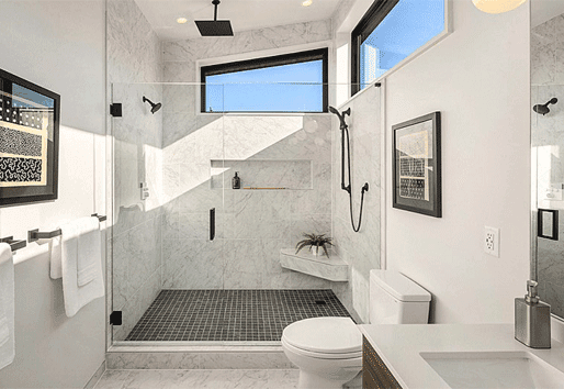 A white bathroom with marble-tiled shower and clerestory windows.