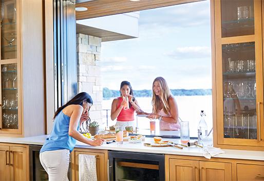 One woman plays bartender from inside while two others gather on the outside of an open pass-through window.