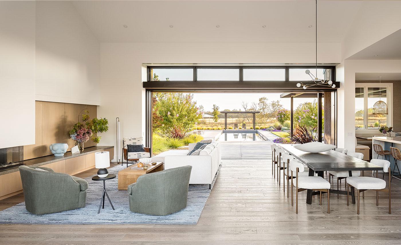 A living room with one wall that completely opens up to the pool area outside.