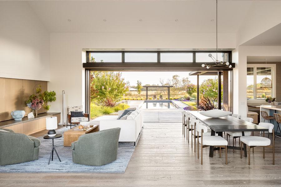 A living room with one wall that completely opens up to the pool area outside.