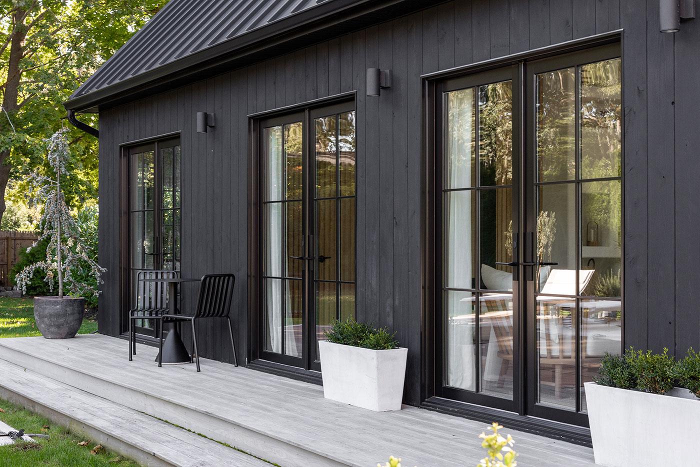 A set of three French doors connect to a wooden deck outside.