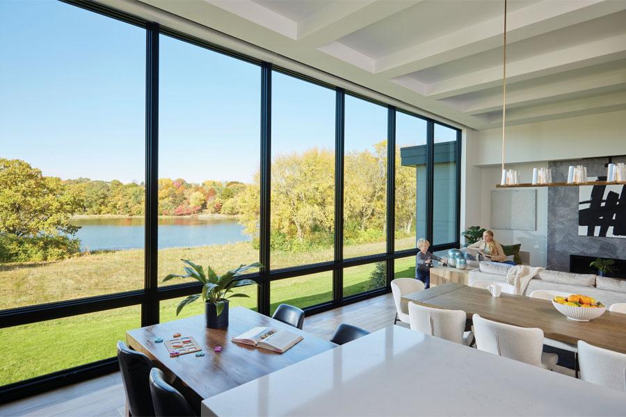 An open concept kitchen-living room with a wall of picture and awning windows facing the backyard. 