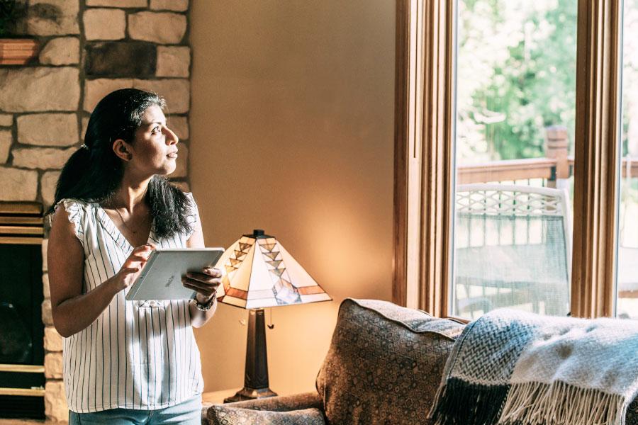 woman holding iPad looking out window