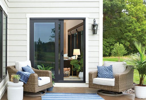 A black sliding patio door is featured with an outdoor patio that has two chairs.