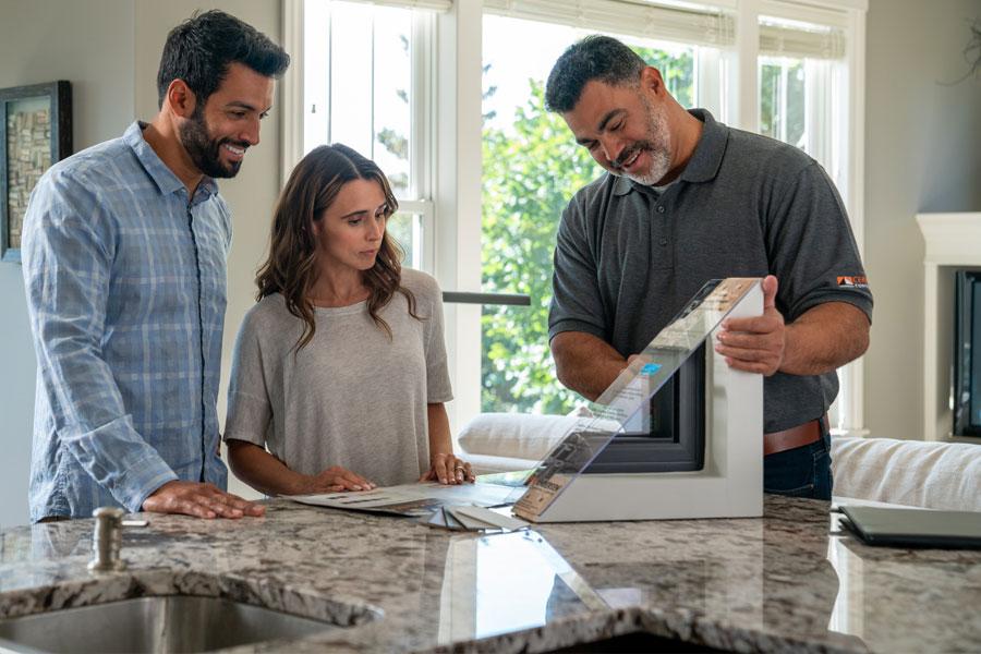 Replacement contractor showing clients a window model in a kitchen