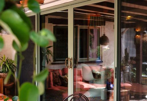 An exterior photo of Justina Blakeney’s olive, two-panel 200 Series Narroline Gliding Patio Doors with Albany hardware.