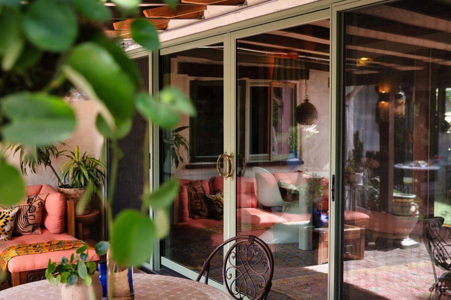 An exterior photo of Justina Blakeney’s olive, two-panel 200 Series Narroline Gliding Patio Doors with Albany hardware.