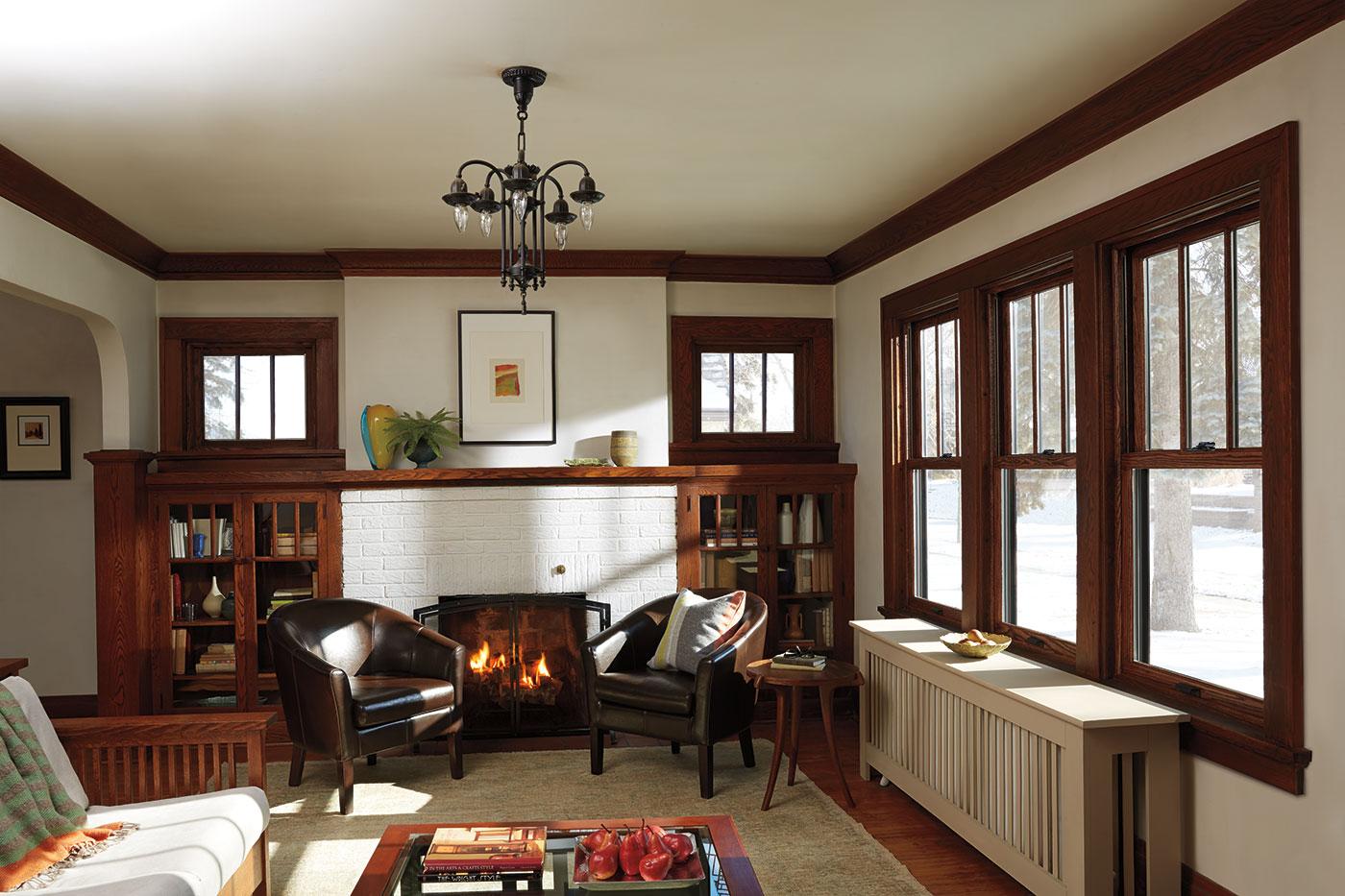 A cozy living room with natura light streaming through the windows and a fire in the hearth.