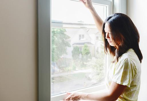 closeup of Woman opening andersen white vinyl window