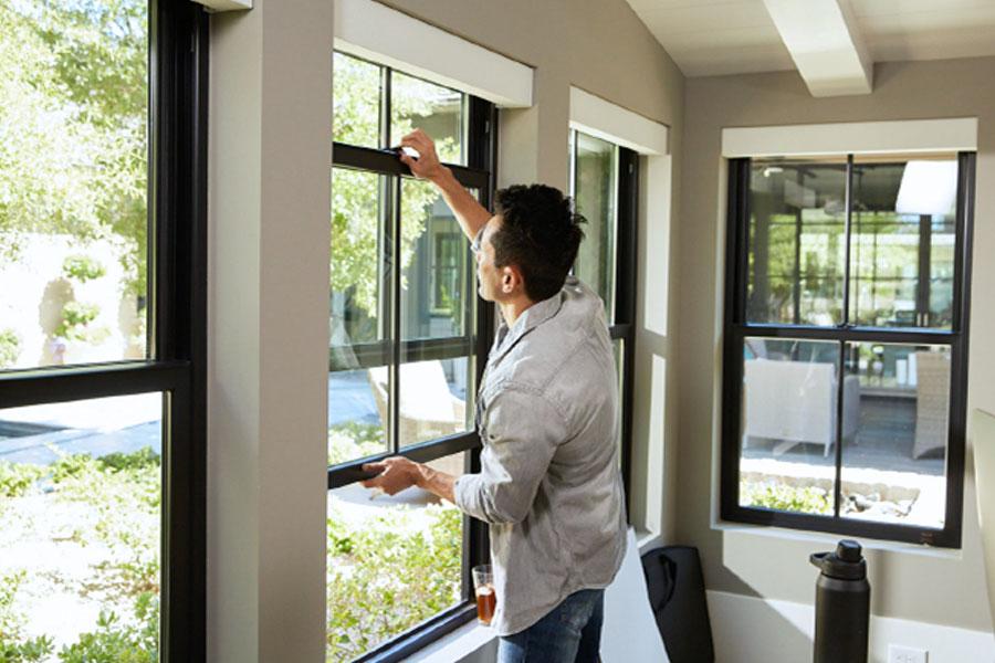 Man opening single-hung window on a beautiful day