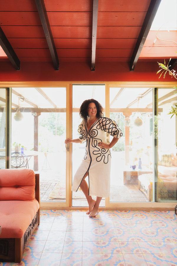 Justina Blakeney poses near her four-panel E-Series Gliding Patio Door with olive exterior, pine interior and a bi-parting opening that makes for a seamless connection between her lanai and courtyard.