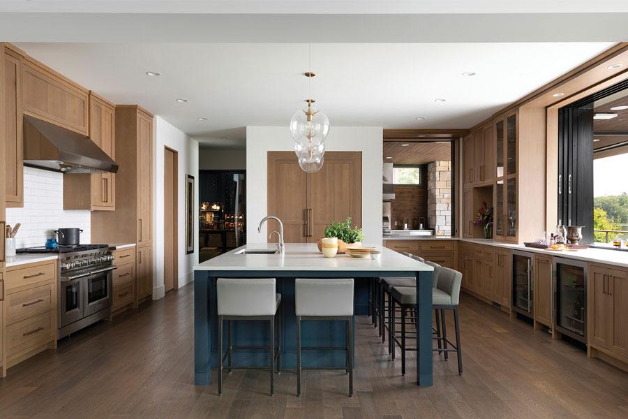 A white kitchen with white oak cabinetry, large center island, and two pass-through windows.