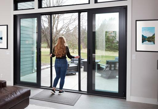 woman walking out to patio with black framed andersen sliding door