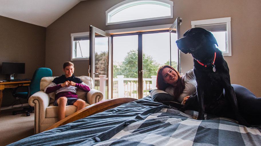 People and dog sitting in bedroom with Andersen Windows and Doors